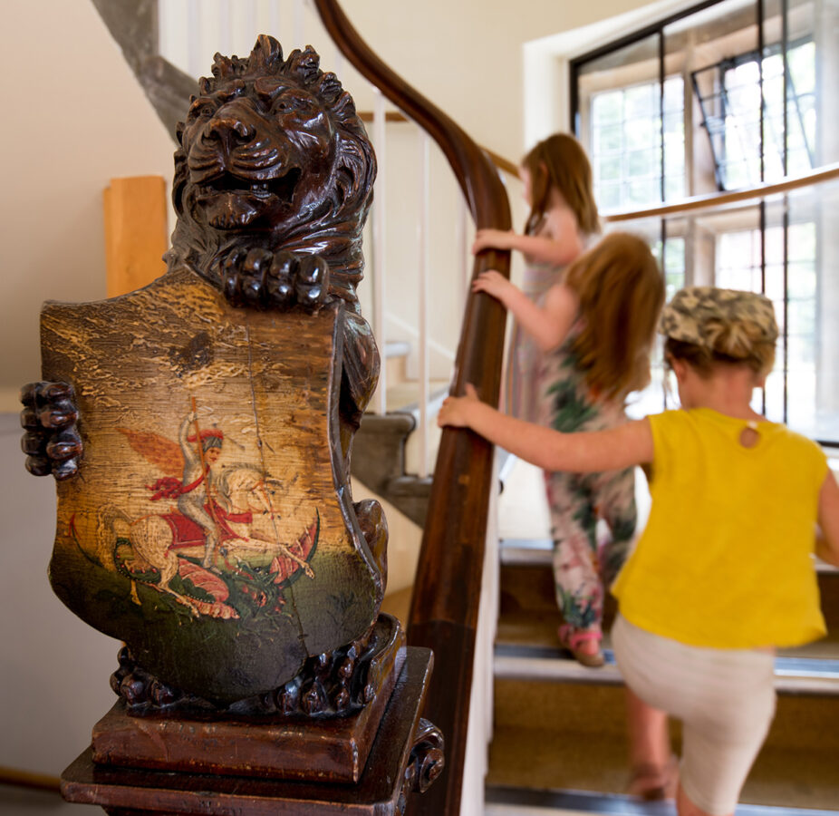 Three Kids Climbing Stairs, in the foreground is a wooden lion holding a shield