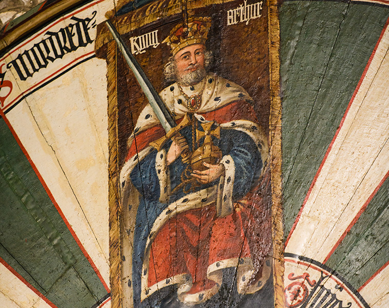 A close up of King Arthurs round table, featuring a painting of King Arthur