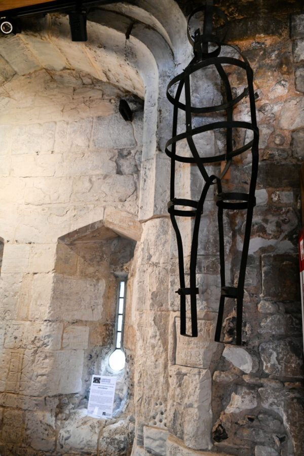 A metal restraining device in black is on an old castle wall