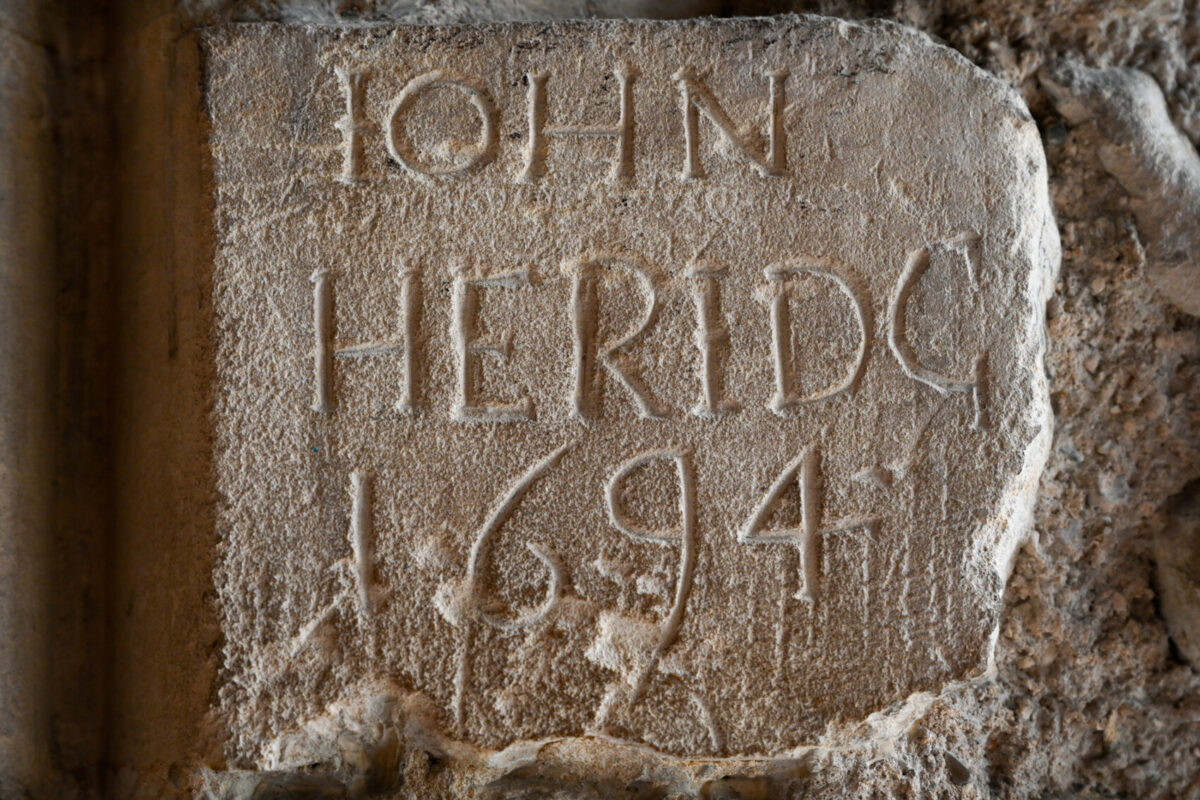 Graffiti etched into a stone wall from 1694