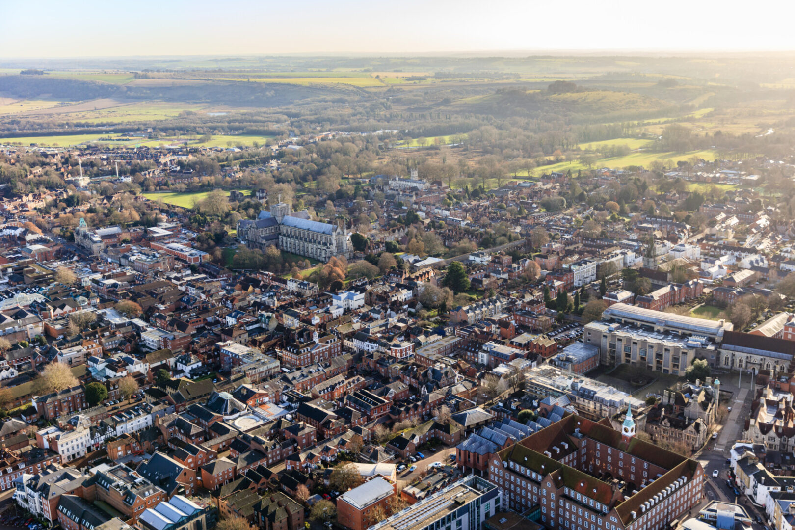 An aerial view of the city of Winchester featuring old and new buildings as well as fields in the distance.