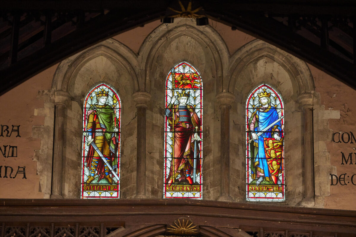 Three thin stained glass panels depicting men with swords and crowns