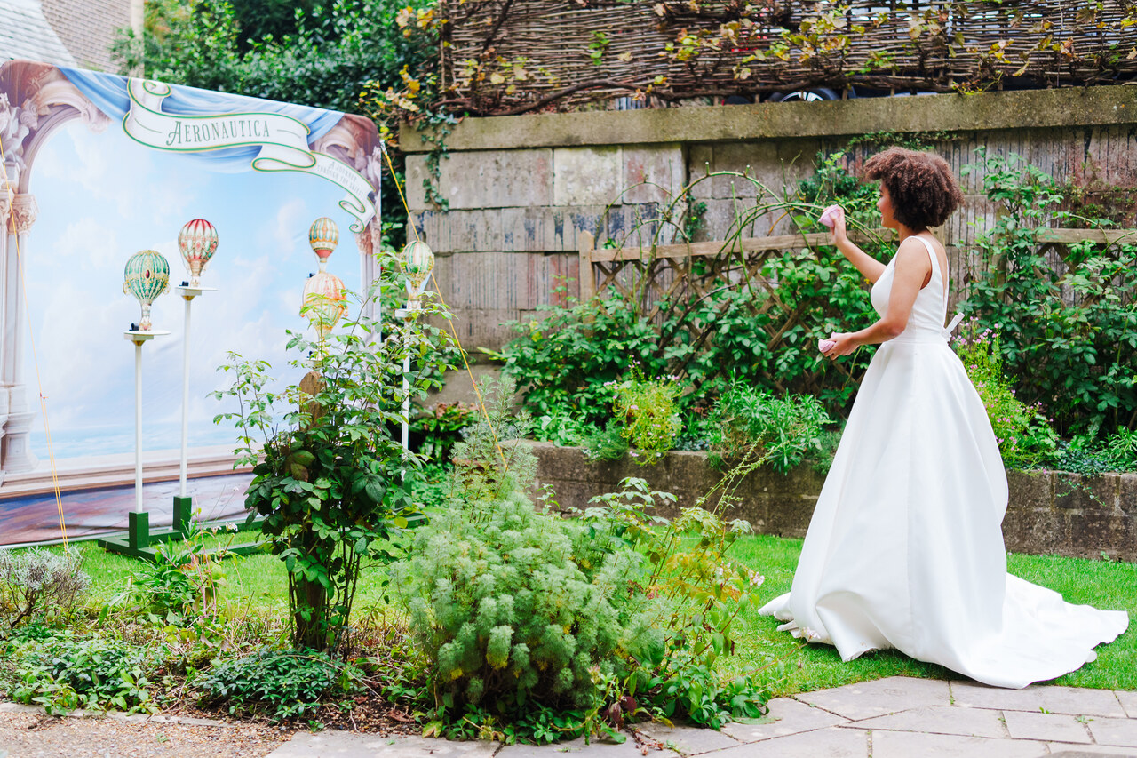 A lady in a white wedding dress plays a garden game