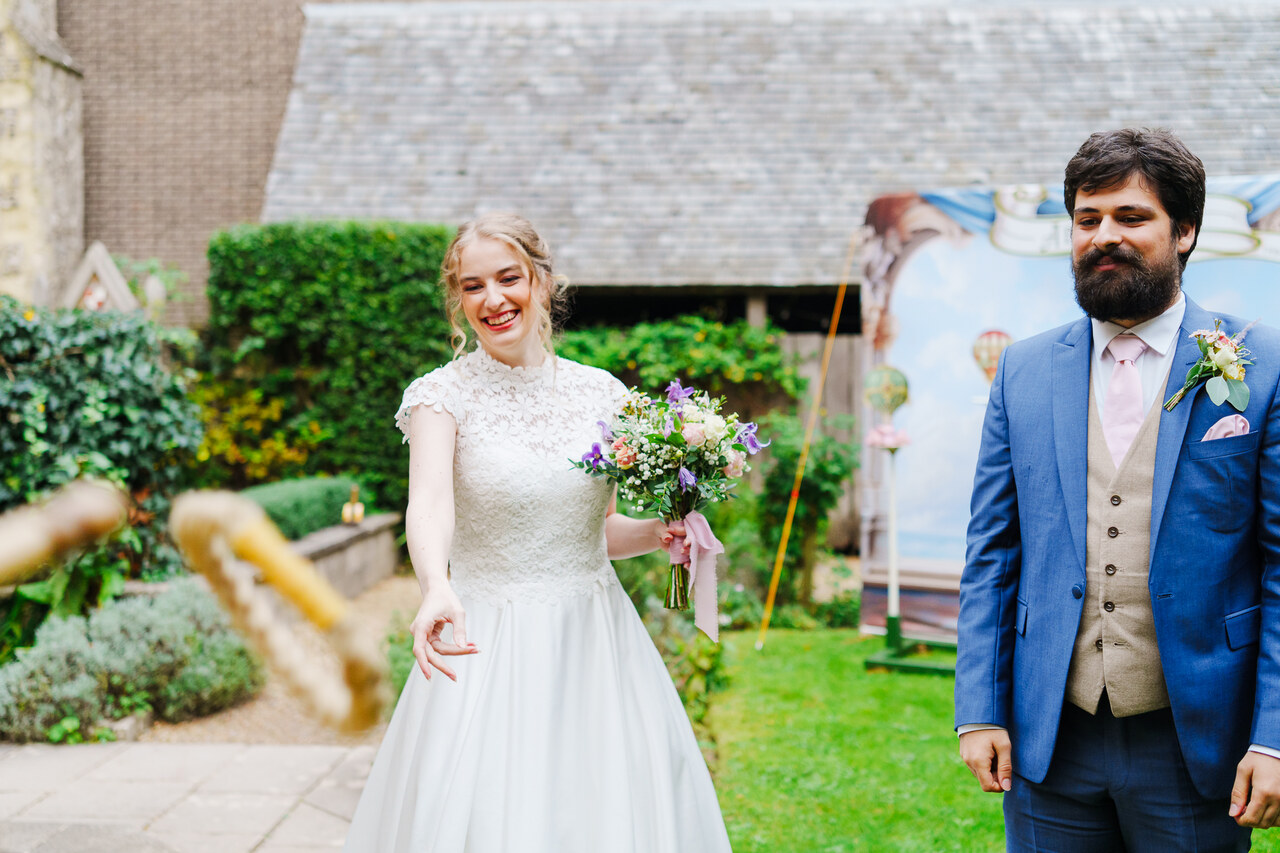 A couple in wedding attire play a garden game in the spring.