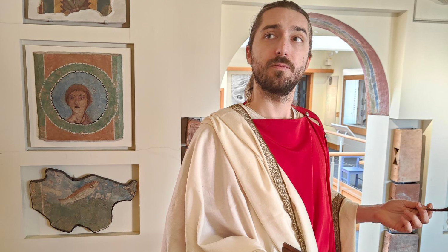 A contemplative Roman standing in front of the Roman paintings in the museum.